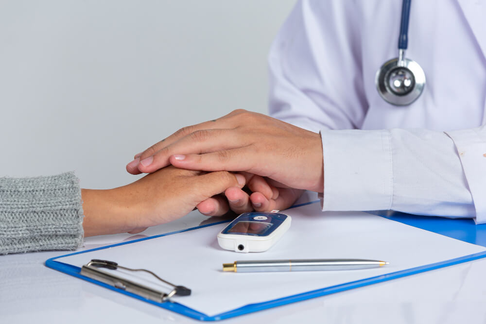 A clinician listens attentively to an older male patient during a consultation.
