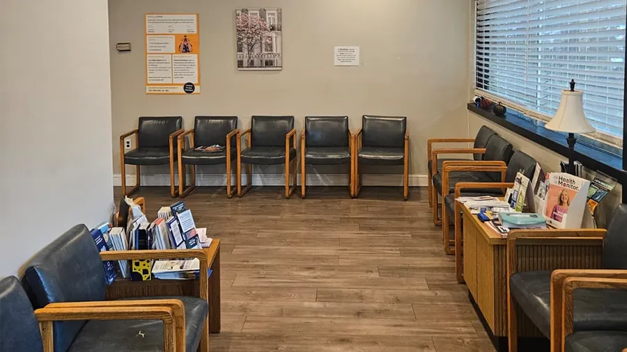A bright, tidy patient waiting room with rows of chairs and health brochures at a New York Total Medical Care office.