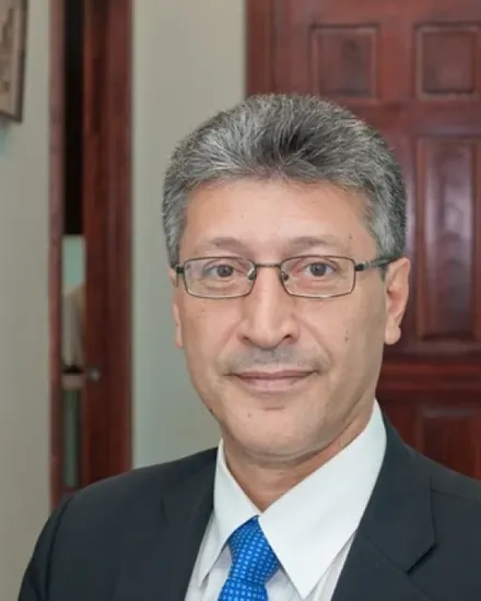 Portrait of Dr. Calogero Tumminello, MD, wearing glasses and a suit